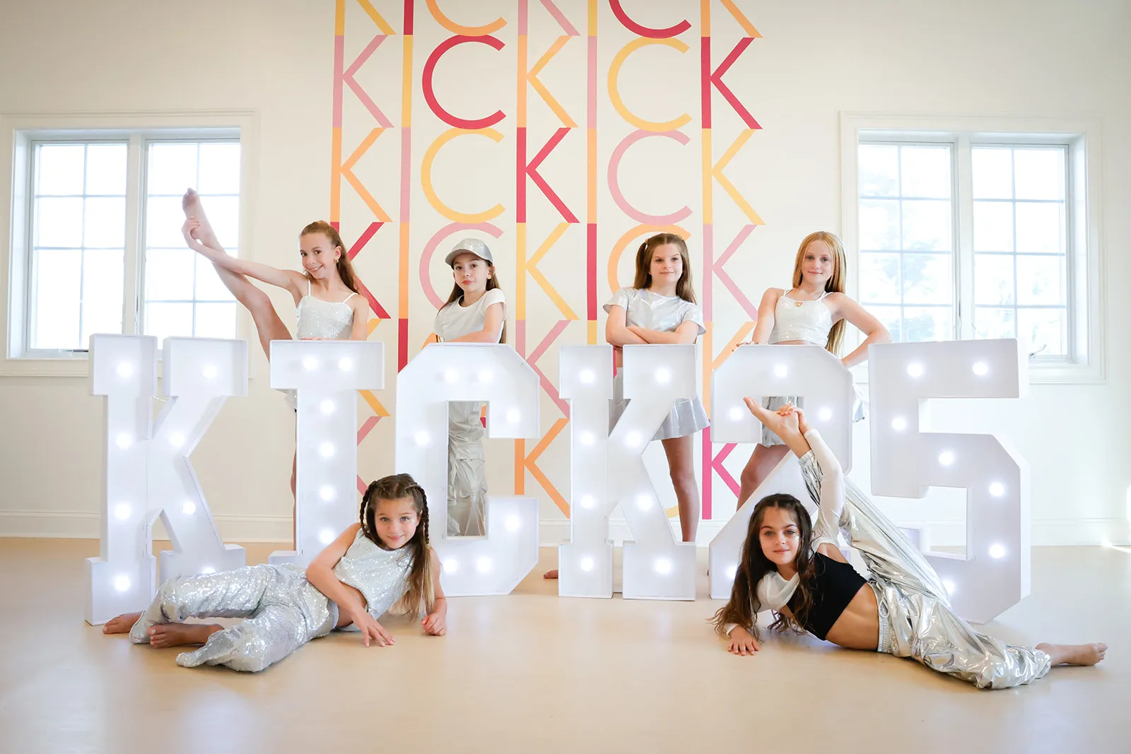 KICK dancers posing among light-up KICK letters