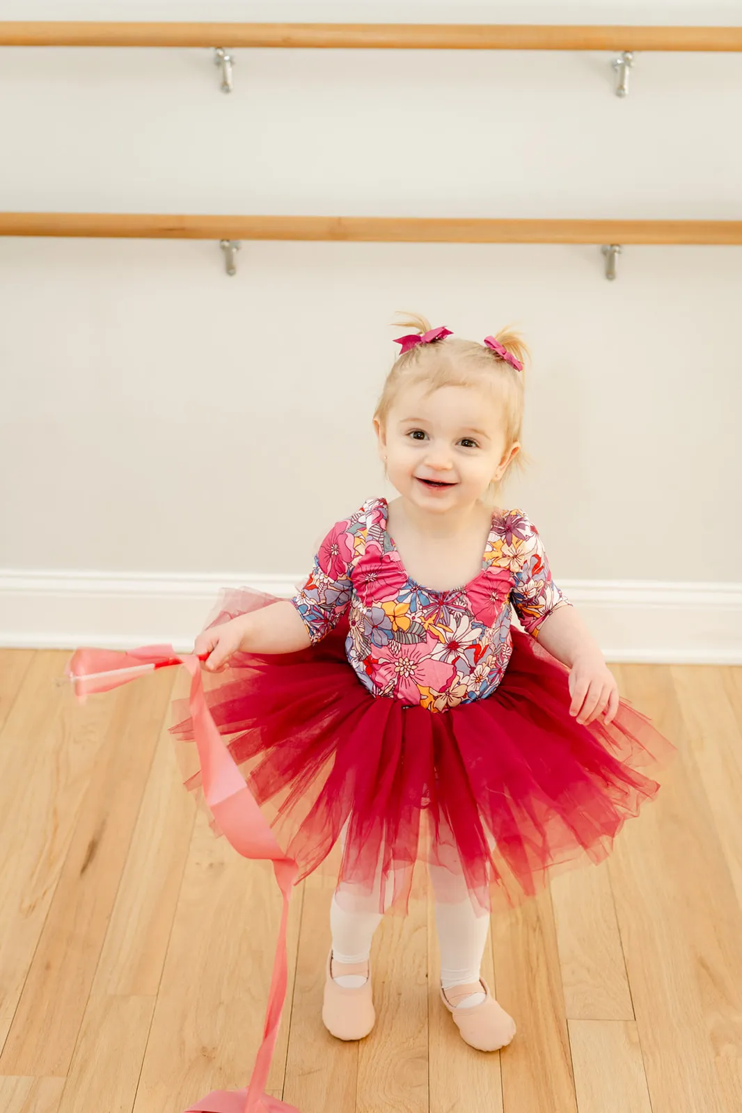 A toddler in a red tutu dancing in the studio